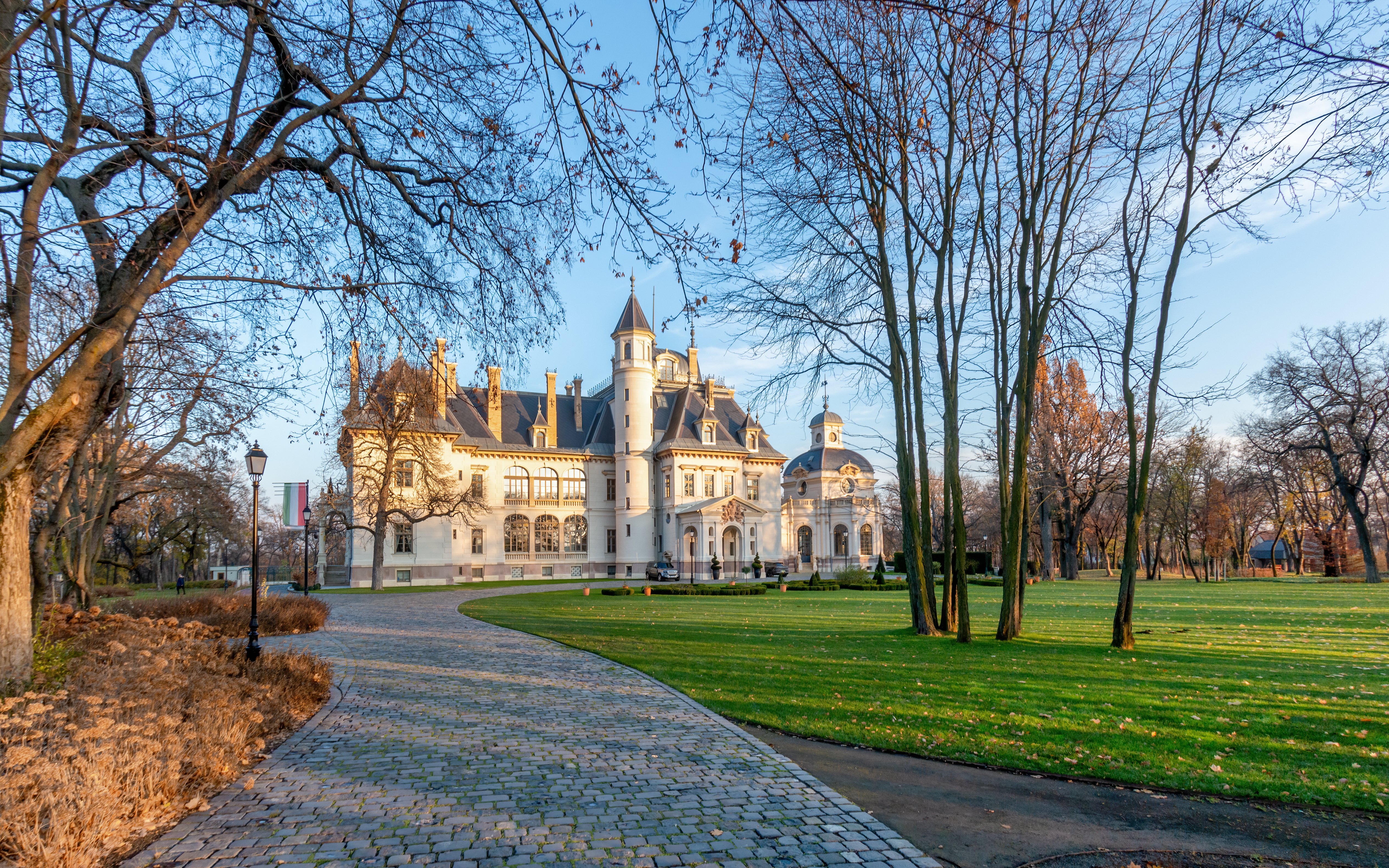 A fairytale come to life, Castle of Tura is a Hungarian masterpiece with architectural beauty emanating from the long driveway and surrounding 10-acre forest. Straight out of a modern storybook, the castle is a seamless blend of 19th-century glamour with contemporary elegance.  Read more to discover this castle’s exceptionally stylish accommodation, which is available to reserve on Reservest for exclusive use. A Hungarian Love Letter This castle was built in 1883 at the behest of Baron Sigmund Schossberger, who desired to create a physical display of his love for his wife, Therese Mayer von Gunthof. A complete renovation of the castle was undertaken in 2016, following years of neglect and weathering. With specialists of the restoration trade, the historic building received a facelift, while maintaining the original design and iconic clock tower. Presently, the romantic castle finds itself enveloped by a green sea of forest and a glittering lake, adding to the fable-esque ambience of this property. Exclusive-Use Castle Reservest offers the castle on an exclusive-use basis, where 19 bedrooms are available for 38 guests. A wide variety of rooms and suites offer guests a selection of luxury arrangements, all of which are en-suite.  Superior and Deluxe Rooms Two Superior Rooms draped in hues of gold provide picturesque views of the manicured park, while the 10 Deluxe Rooms pay homage to the bedrooms of princesses with their four-poster beds and quiet luxury decor.  Junior Suites The five Junior Suites include a bedroom, en-suite bathroom and living room. Their spacious designs feature golden furnishings with black accents, creating a chic environment. Of course, what suite would be complete without a phenomenal view of the surrounding forest and the castle’s proud flower garden? Executive Suite This suite offers views of the Palm House and Botanical Garden from its private terrace. Long curtains kiss the floor and frame the windows that flaunt picture-perfect views of the magical greenery. Indoors, the decor features botanical motifs in a flourish of deep browns and golds. Additionally, this suite includes a bathtub with a shower, offering a space to relax in privacy. Schossberger Suite Bearing the name of the castle’s baron, this suite is nothing short of exceptional. The chic-meets-stately decor pays homage to the baron and his legacy. A private terrace offers a perfect breakfast and morning coffee nook to gaze upon the castle grounds, while the living and dining area offer a romantic dinner location.  Elevated Gastronomy The castle’s restaurant, Clarrise, is a Michelin-awarded fine-dining spot with dishes influenced by local Hungarian favourites, as well as international cuisine. At Palm House, breakfast is the order of the day, and the á la carte menu sports a wide variety. During the day, BOTANIQ Bar functions as a bistro bar with a curated selection of Hungarian coffees and teas. When evening settles over the castle, guests can expect an award-winning wine menu and spirits from around the world. BOTANIQ Spa The castle’s spa offers guests a Finnish sauna, steam room and salt room, as well as outdoor and indoor pools. The spa’s signature treatment is a full body scrub and facial treatment that consists of a clay-based cream, nourished with field horsetail and calendula. Treatments are 100% free of chemicals and vegan, assuring guests that their wellness is the spa’s utmost priority.  Beyond the spa, guests can discover the modern fitness facilities (featuring cardio and weight equipment). The yoga terrace is located outdoors, providing a holistic space for obtaining a harmonic balance. And for tennis lovers, the court is ready for overhead shots and the echoing squeak of sneakers in the quiet of the forest. Reservest Partners with BOTANIQ Castle of Tura Discover this truly unique property   on Reservest—a seamless booking engine offering travel experts thousands of luxury suites and villas. Click the link to sign up and access trade rates for a magical experience at BOTANIQ Castle of Tura.